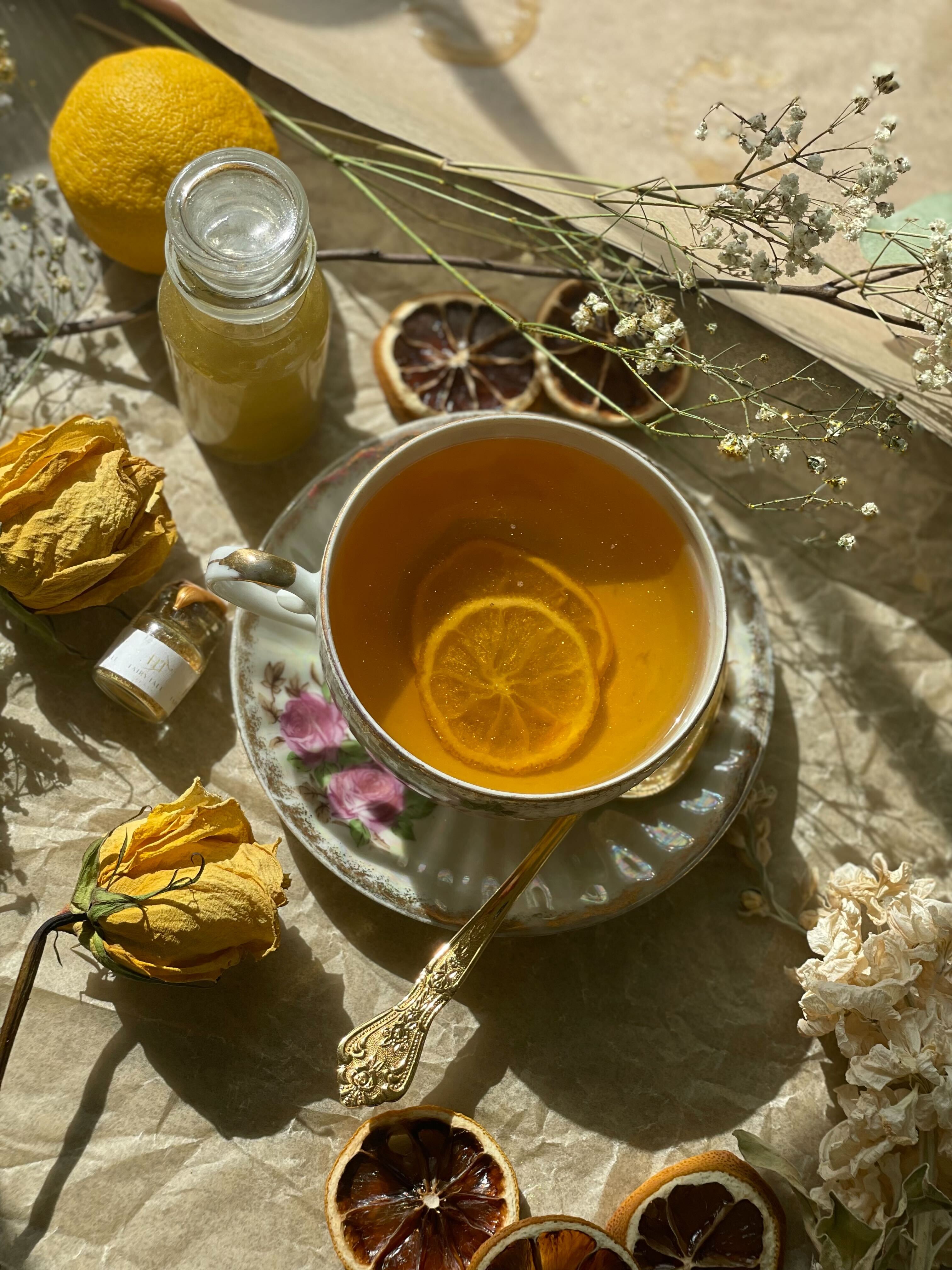Cup of gilded lily with candied lemon slices next to a bottle of Golden Pixie Dust from Fairy Tale Teas